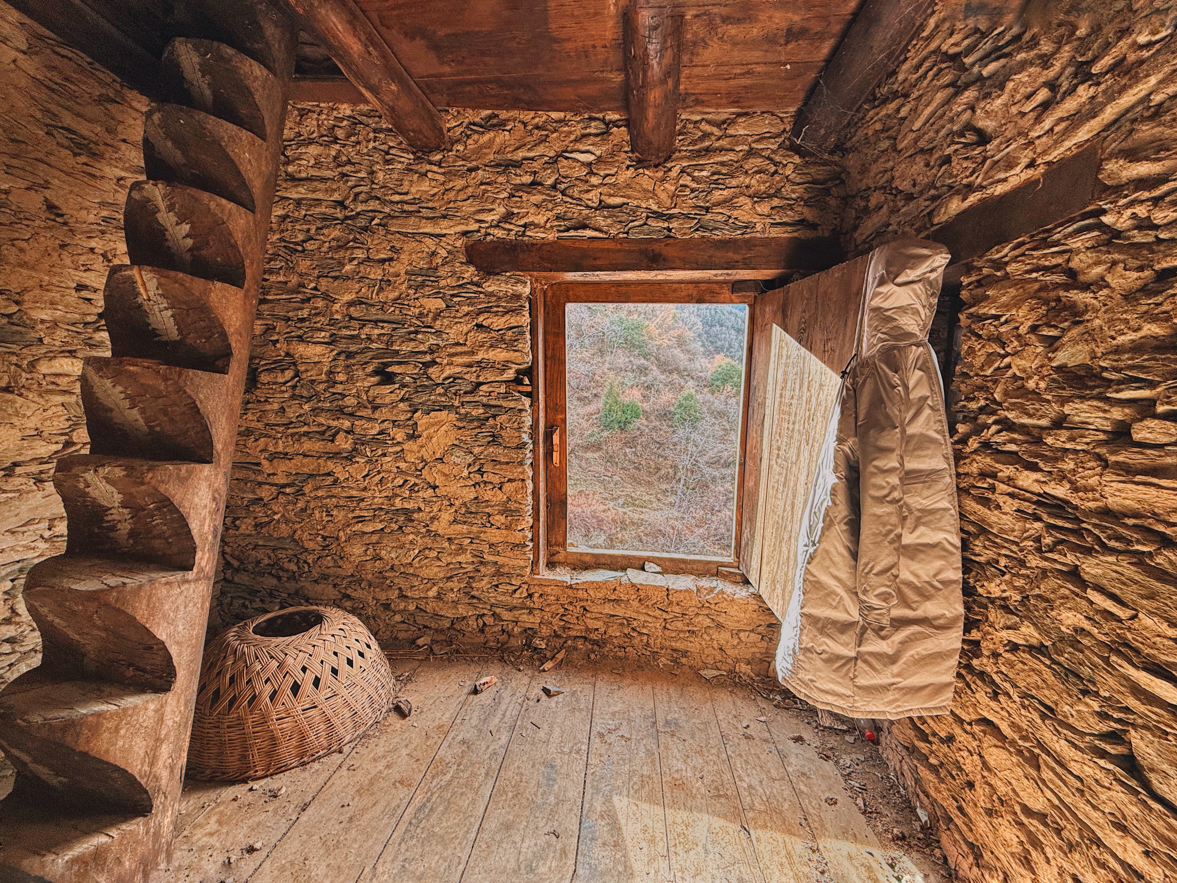 Interior of a Qiang village house with stone walls, wooden beams and a window.